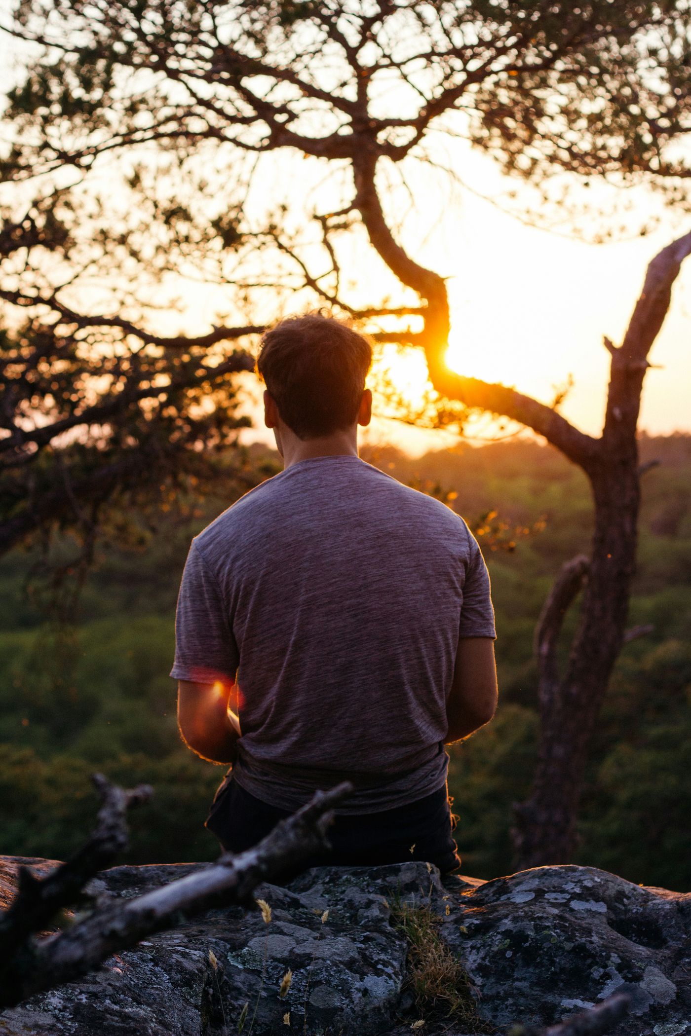 A man sitting at sunset looking downcast, representing low mood and depression in men, therapy online in Ontario