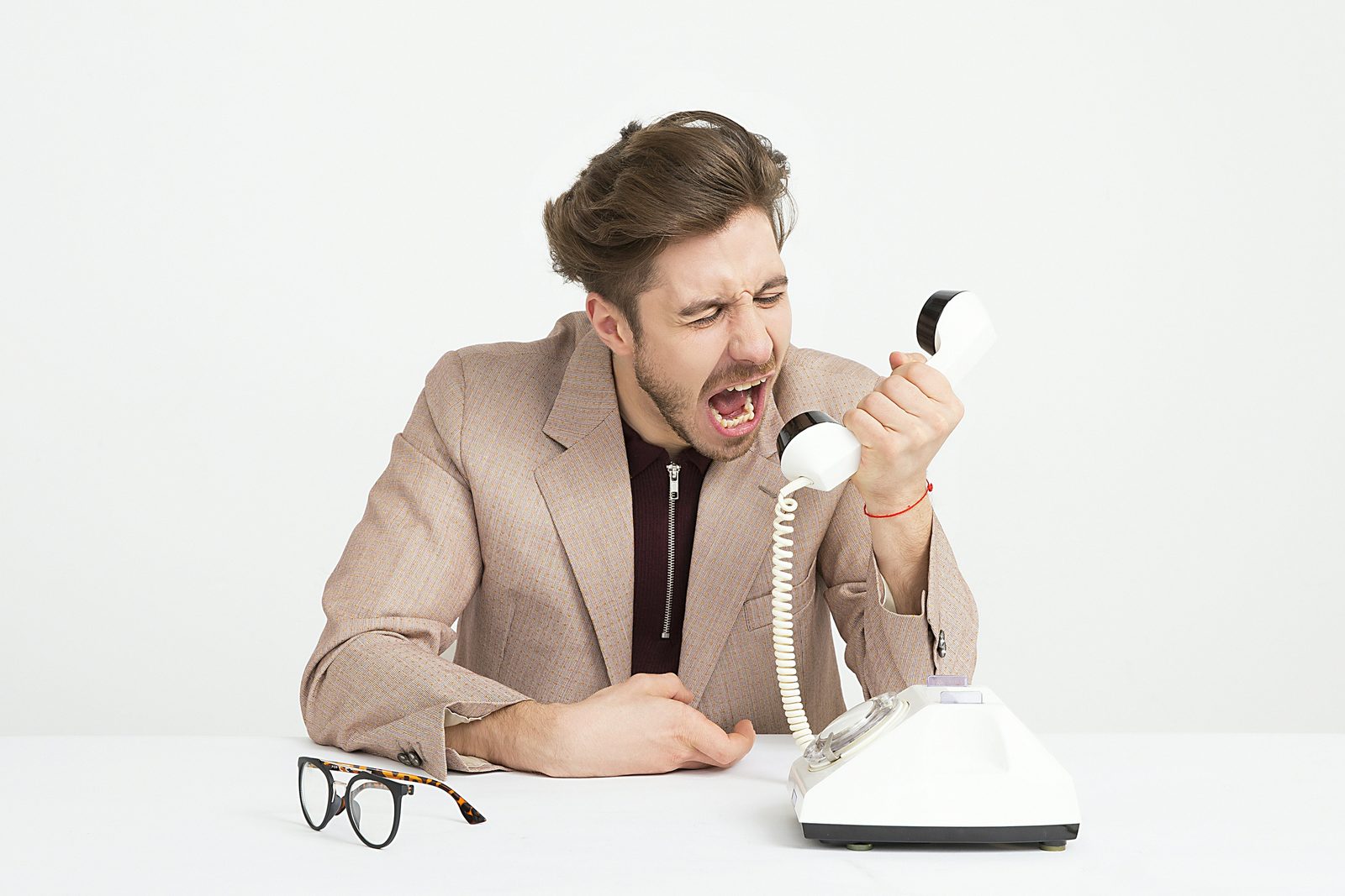 A frustrated man reacting in anger at his phone, representing what anger is trying to signal, men's therapy in Ontario